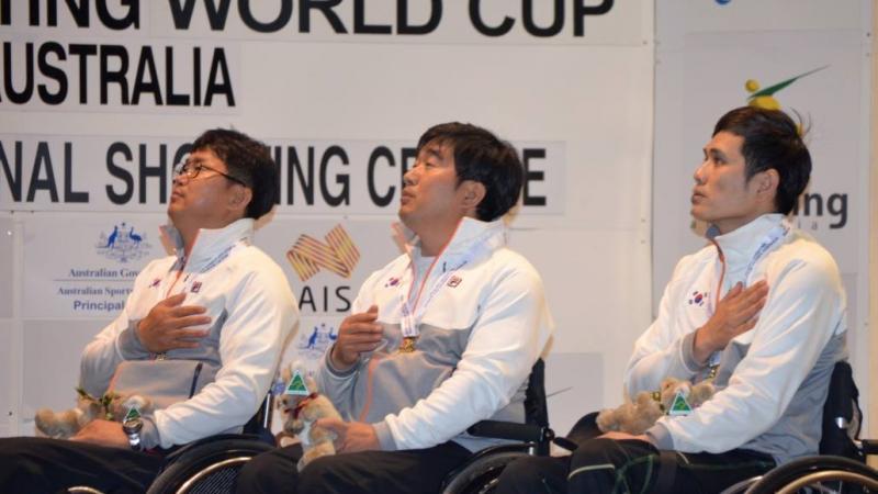 Three men in wheelchairs, having their hand on their chest