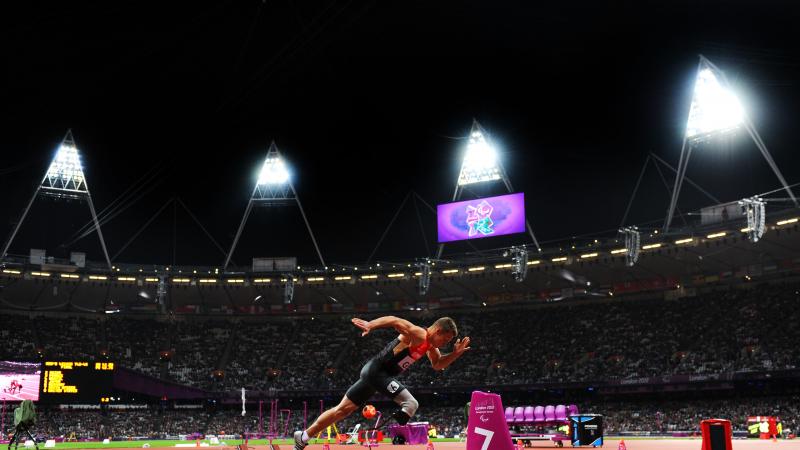 Man in a full stadium, starts sprinting from starting blocks