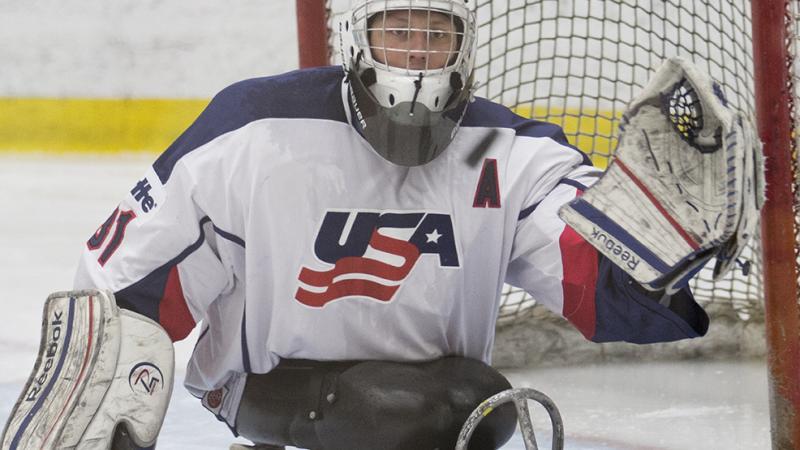 Man in ice sledge hockey uniform on a sledge on the ice