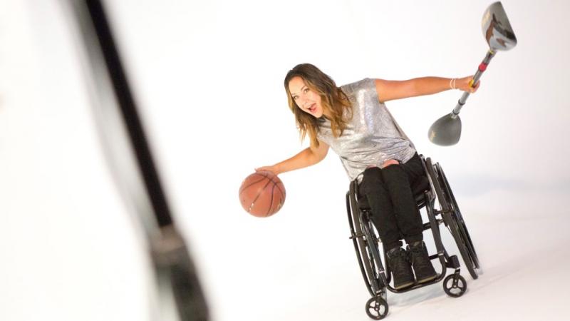 Woman in wheelchair with a basketball and a paddle in her hands