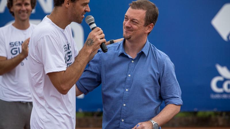 Two men on a stage, on speaking into a microphone