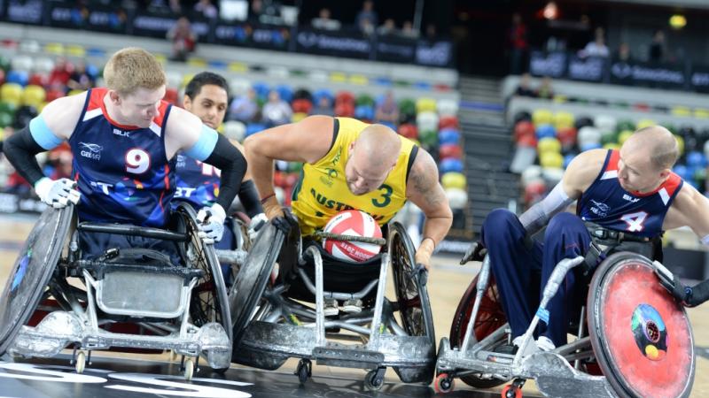 wheelchair rugby player in yellow jersey defending the ball