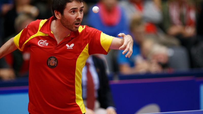 Man in red jersey focusing on a table tennis ball