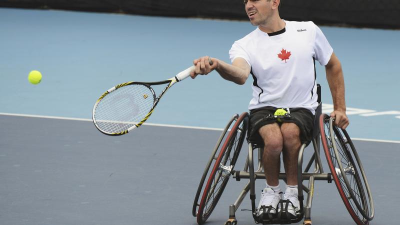 Man in wheelchair returns a tennis ball