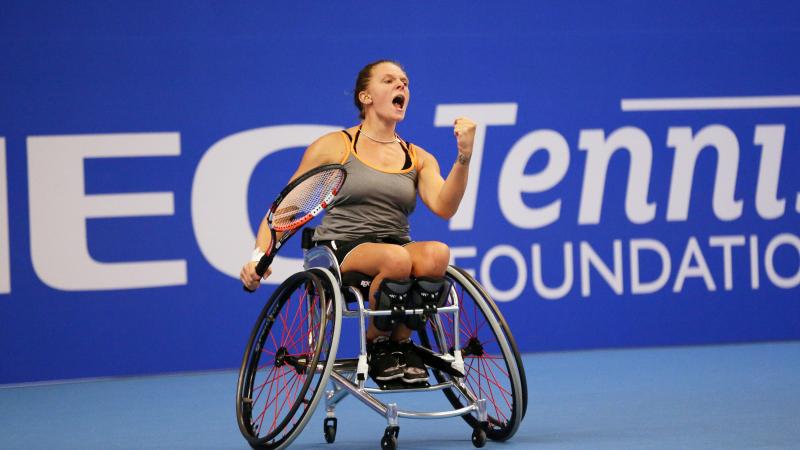 Woman in wheelchair celebrates after wheelchair tennis point