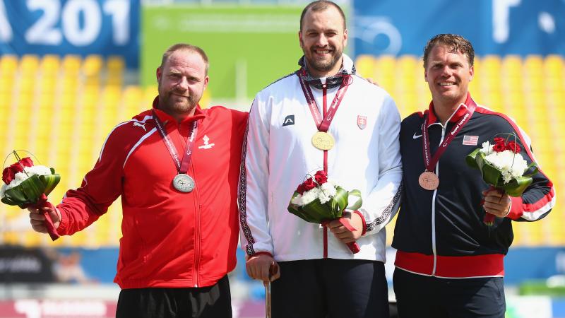 Podium with three men showing their medals