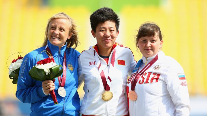 Podium of three women showing their medals