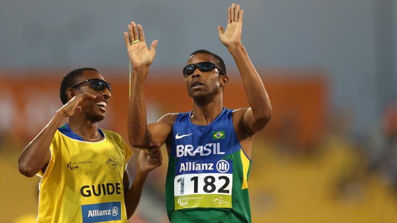 Blindfolded man and guide celebrate after crossing the finish line