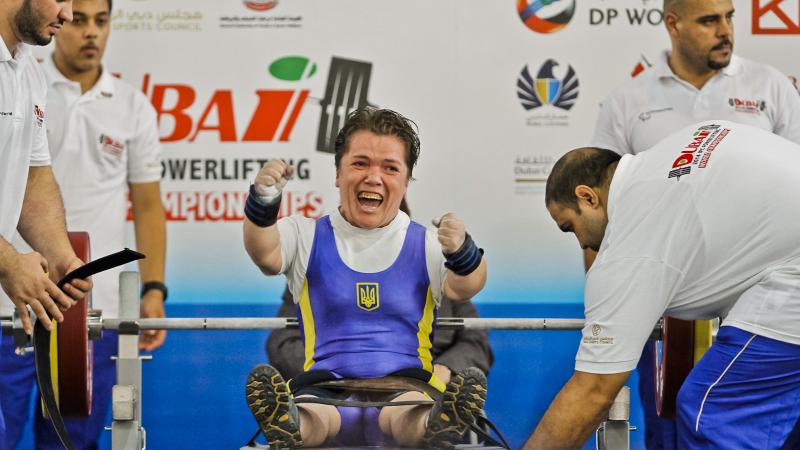 A powerlifter with short stature celebrates on the bench