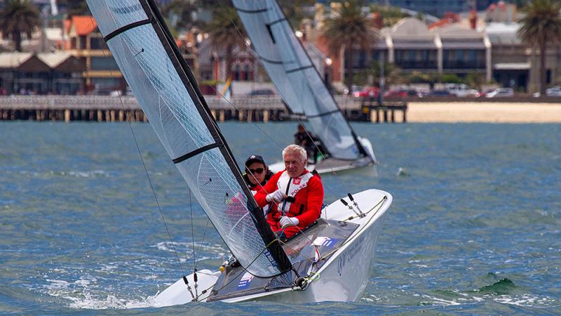 Two sailors in a boat on the water, wearinf red jackets