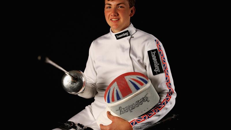 Man in wheelchair with a foil smiling to the camera