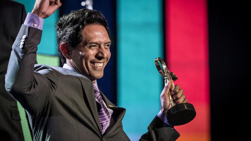 Upper bory of smiling man, holding up a trophy