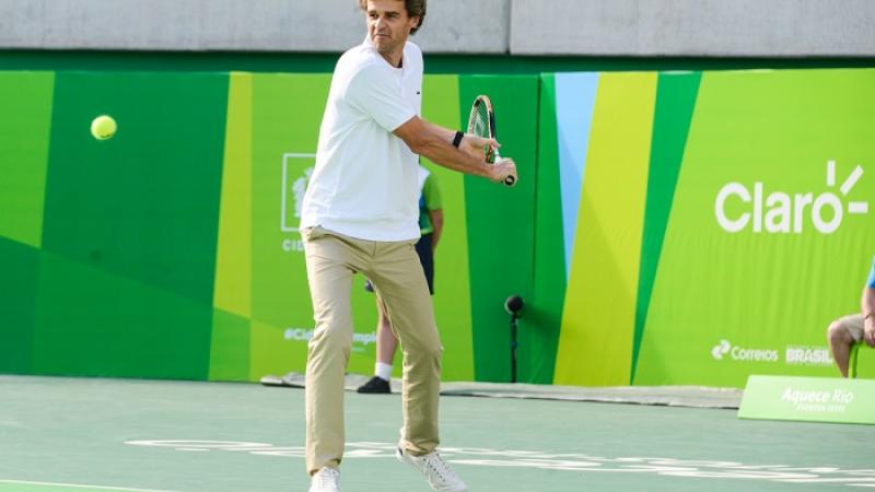 Man holding tennis raquet about to hit the ball