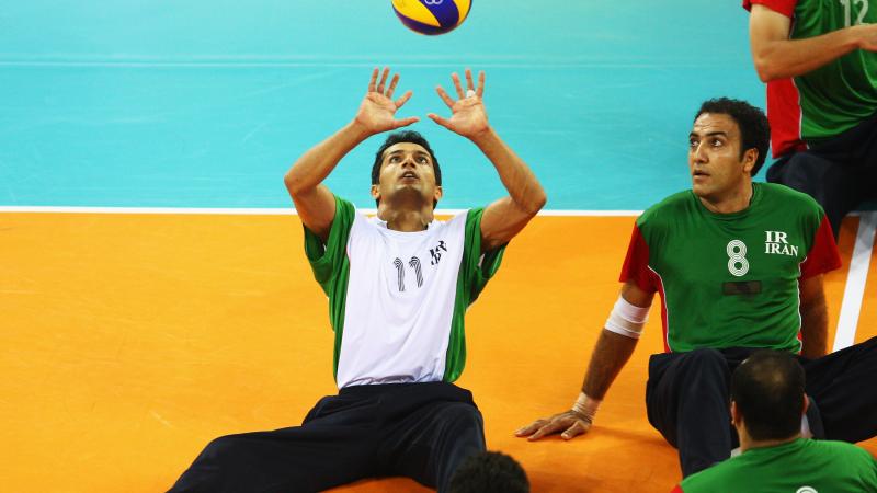 Man hits a volleyball in the air 