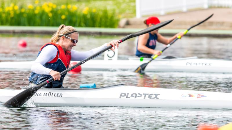 a photo showing the top half of a lady in a canoe wearing a white top, life jacket and sunglasses