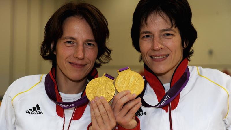 A shot of the upper half of two women holding two Paralympic gold medals