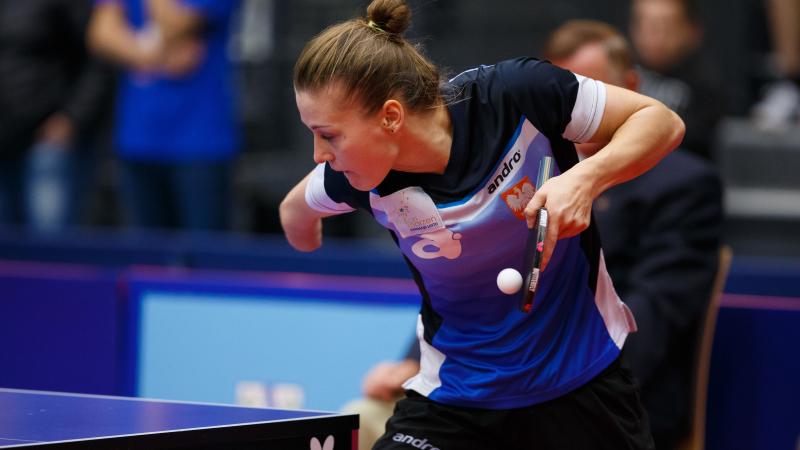 a female wearing a navy and blue shirt playing table tennis