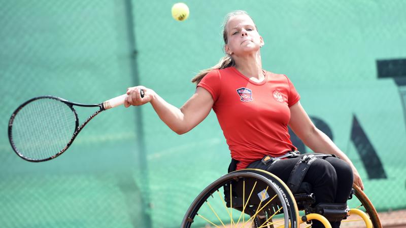 Girl in wheelchair hits a forehand return.