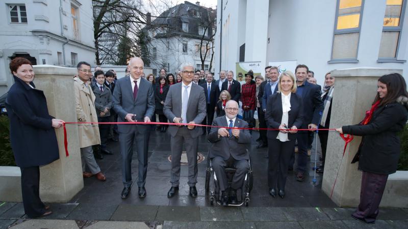 Picture of four people cutting a red ribbon to open a new building.