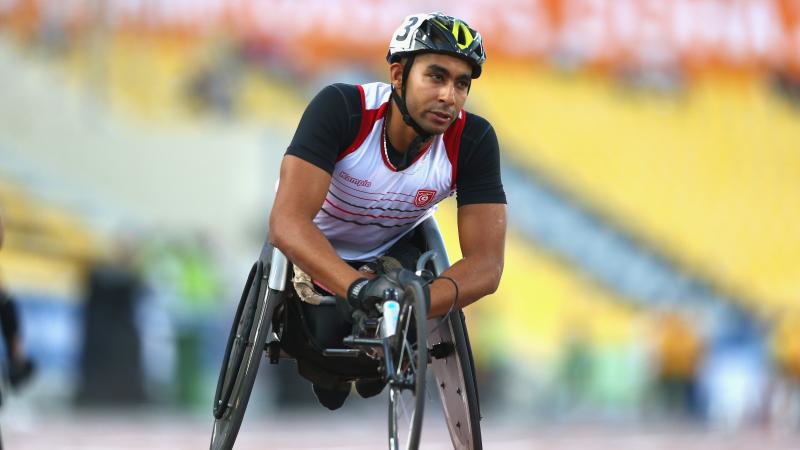 a male from Tunisia wearing a helmet and racing in a wheelchair