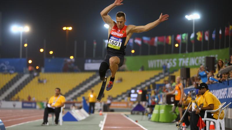 a male from Germany wearing red and black clothes competing in the long jump