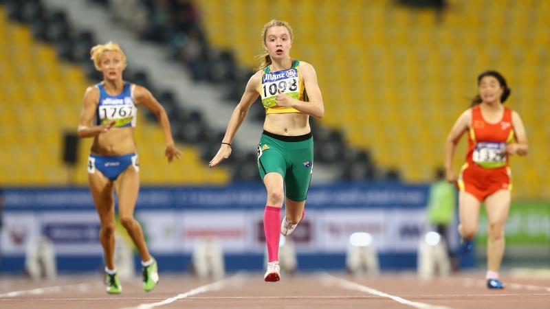 three females running, one wearing green, one blue and one red