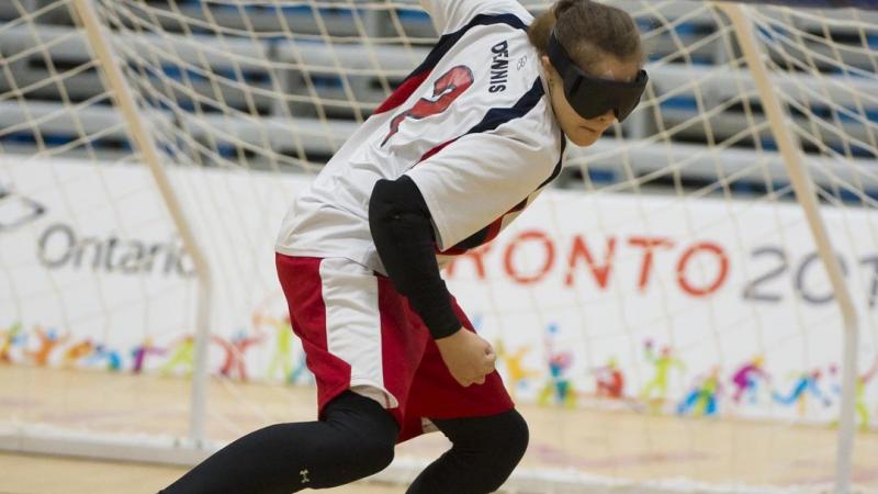 a female wearing white, black and red competing in goalball