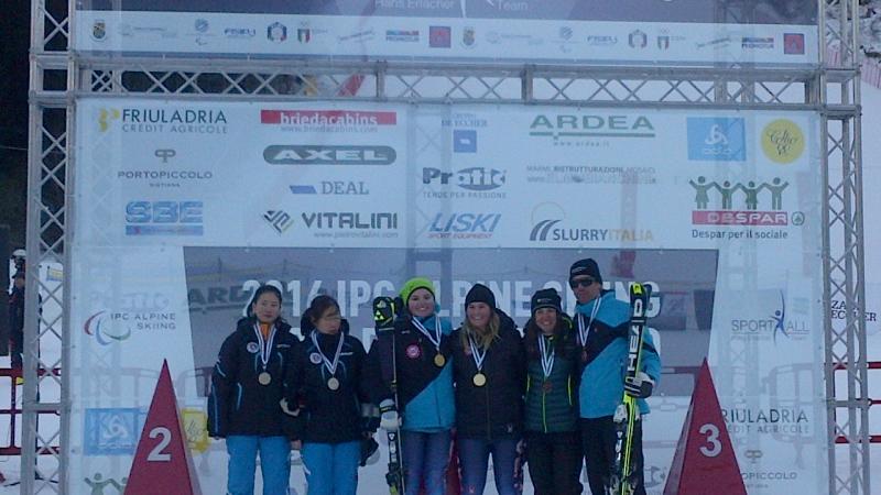 Podium of six people in front of a branded wall