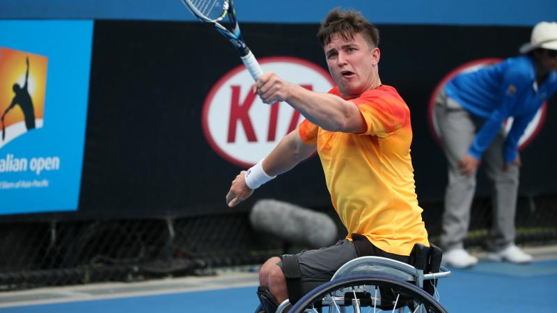 Man in wheelchair, hitting a ball with a tennis racket