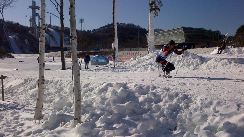 View on a slope with sit skier passing