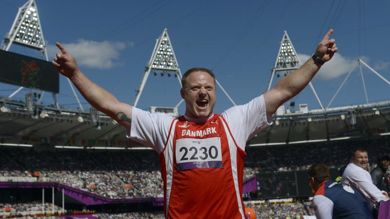 Man in stadium waves his arms in the air, celebrates