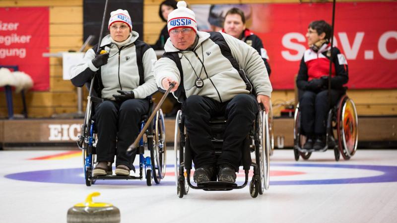 Wheelchair curler on the ice with team in the background