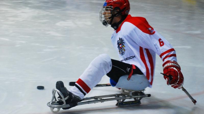 Ice sledge hockey player in red and white jersey on the ice