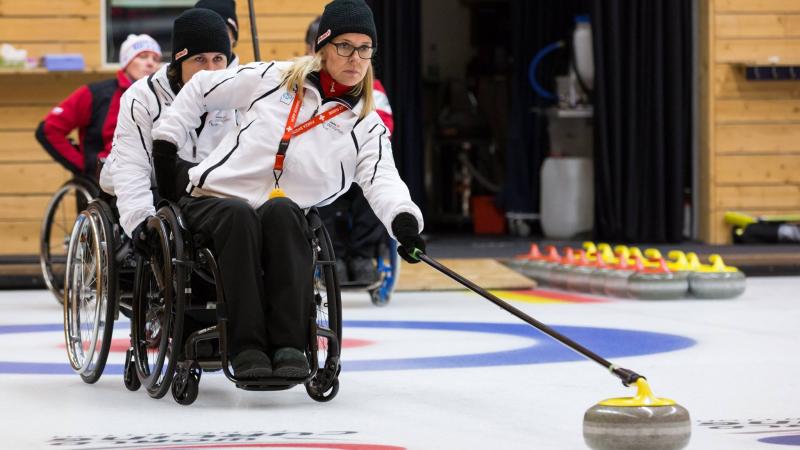 Wheelchair curler on the ice with team in the background