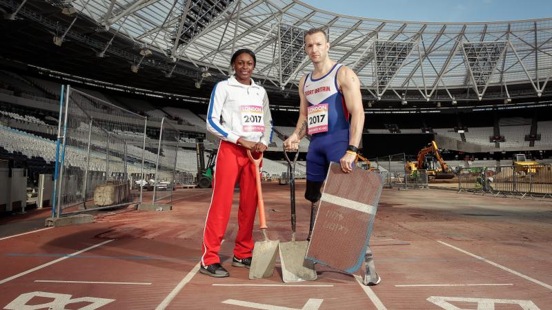 A man and a woman in a stadium, with spadens, working on an athletics track