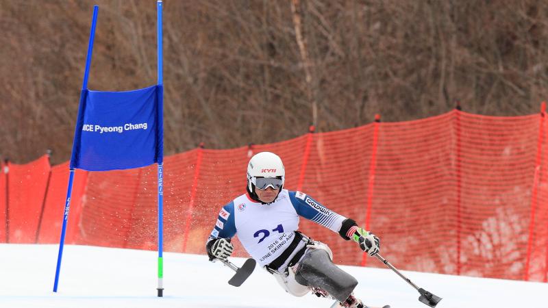 Man in a sit ski passing a gate