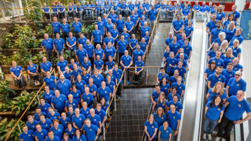 Group picture of many people in blue shirts, shot from above