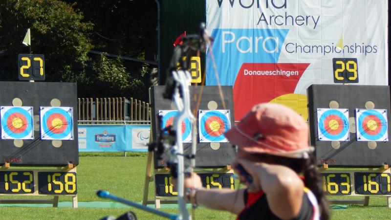 Shot from the back, woman doing archery 