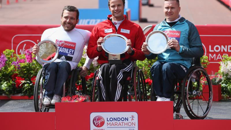 The podium finishers at the 2016 Virgin Money London Marathon - winner Switzerland's Marcel Hug of Switzerland (C), second place Australia's Kurt Fearnley (L) and third place Great Britain's David Weir.