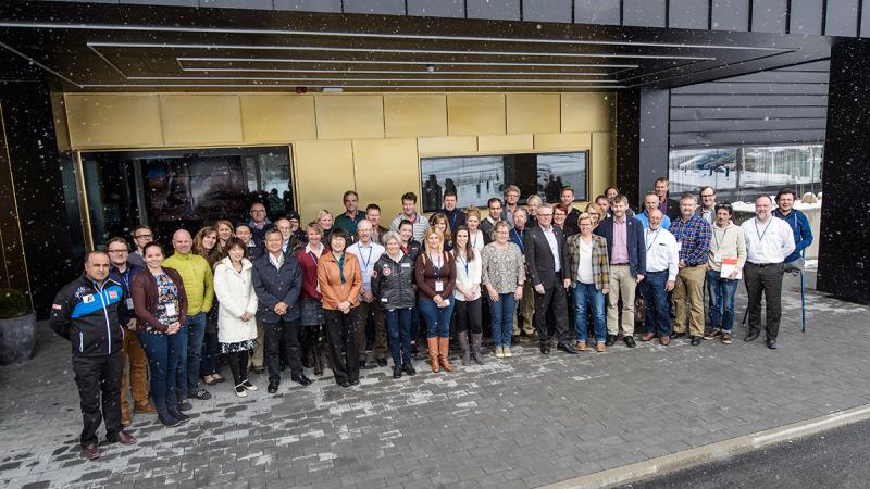 Group shot of 34 people outside a building. It's snowing