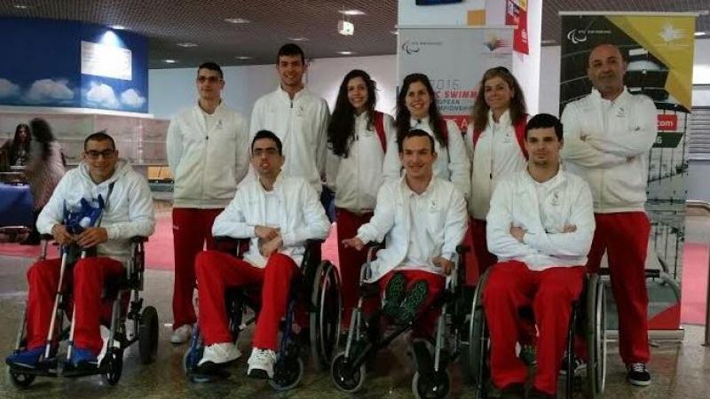 Group shot of athletes standing and in wheelchairs at an airport.