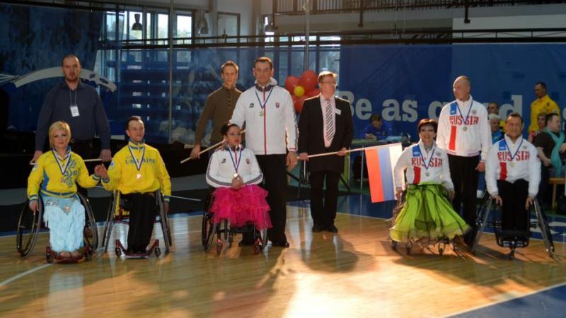 Athletes in wheelchairs and standing pose for a group photo