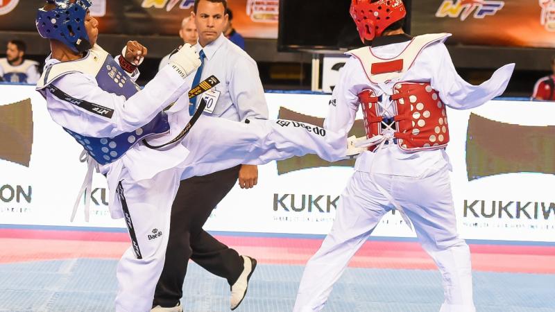 A taekwondo athlete kicks another taekwondo athlete