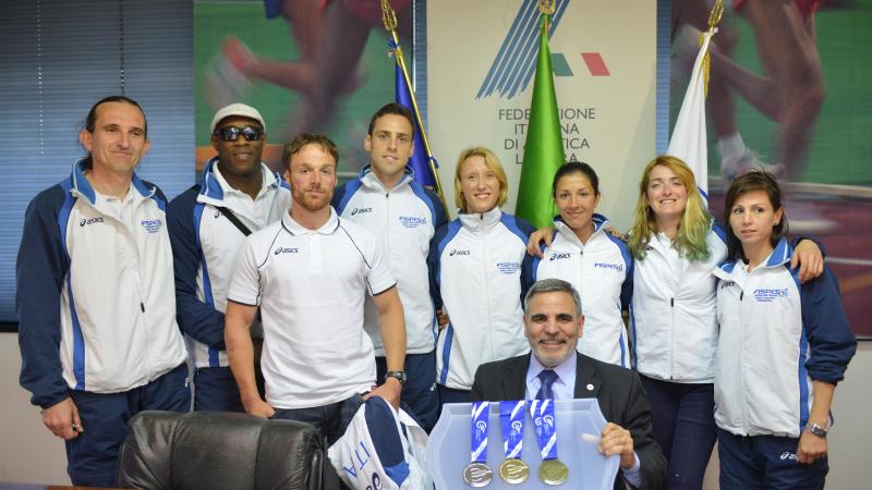 Group of athletes together with an older man showing medals