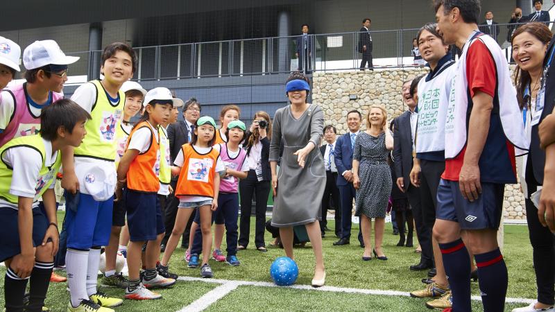 Woman in smart grey dress, blindfolded, surrounded by kids