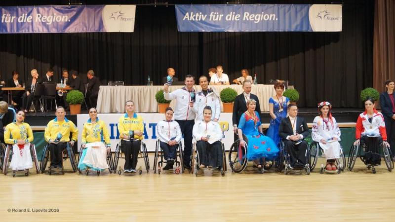 Group picture of people standing and in wheelchairs, showing medals