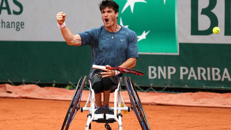 Man in wheelchair on tennis court, celebrating