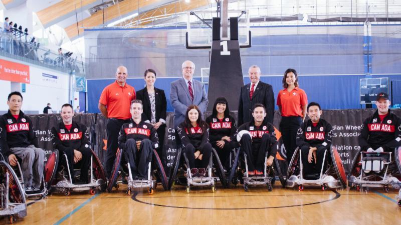 Twelve athletes in wheelchairs lined up, making up the wheelchair rugby team. 