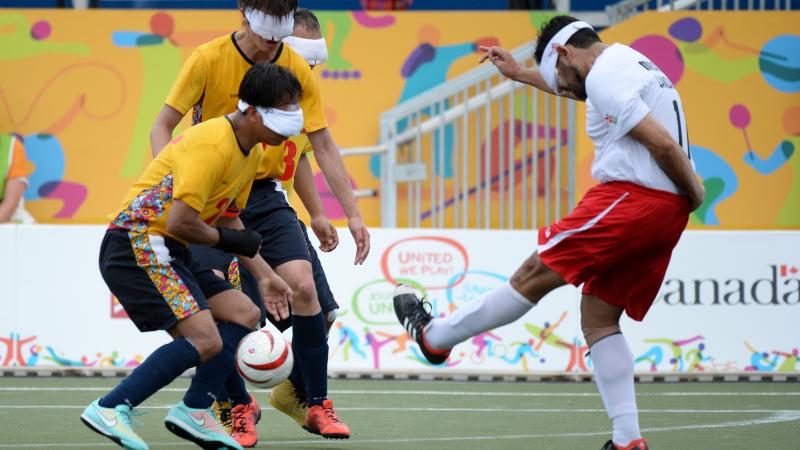 Three blind athletes playing football on a field at the Parapan American Games