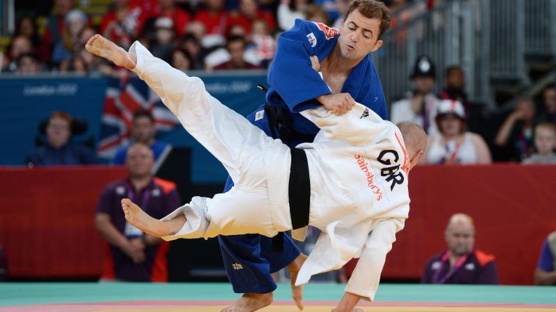 Two judo athletes fighting on a tatami or judo mat. 